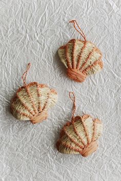 three woven baskets are sitting on a white tablecloth with twine strings hanging from them