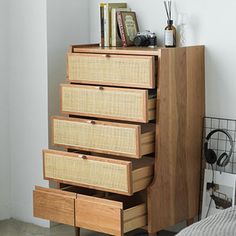 a wooden dresser with drawers and headphones on it's shelf next to a bed