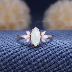 an opal and diamond ring sitting on top of a blue blanket