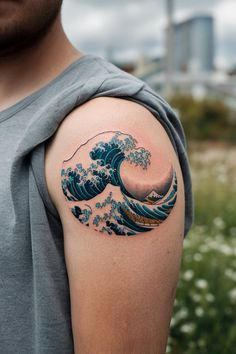 a man with a tattoo on his arm that has an image of the great wave