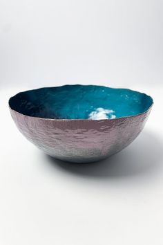 a blue and silver bowl sitting on top of a white table