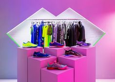 a display case filled with lots of different colored shoes and clothing hanging on hooks in front of a pink wall