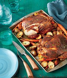 a roasting pan filled with chicken, potatoes and carrots on top of a table