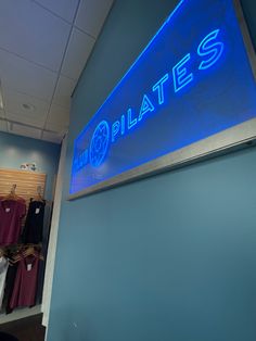 a blue sign that reads pilates hangs on the side of a wall in a store