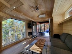 a living room filled with furniture next to a window covered in wooden planked walls