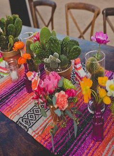 a table topped with potted plants on top of a wooden table covered in colorful cloth