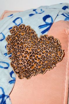 an animal print heart shaped pillow on top of a pink and blue blanket with the word love written across it