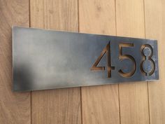 a metal house number sign mounted on a wooden wall with the numbers 45 and eighty