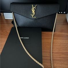 Saint Laurent Uptown Pouch In Black Leather With Gold Tone Hardware In Like New Condition, Comes With ***Black Insert & Unbranded Gold Purse Chain Strap Which Is Detachable. - See Last Photo, Shows Tan Insert - Will Be Black To Attach. Original Dust Bag & Authenticity Card, & Ysl Box. Made In Italy Authentic Ysl! Dimensions: 27 Cm Length / 16 Cm H / 2 Cm D Gold-Toned Metal Hardware Magnetic Closure Interior: One Main Compartment 100% Calfskin Leather Like New. Fits Any Size Phone, Iphone Max * Smoke Free & Pet Free Ysl Uptown Pouch, Ysl Box, Gold Purse, Yves Saint Laurent Bags, Metal Hardware, Gold Tone Metal, Magnetic Closure, Chain Strap, Yves Saint Laurent