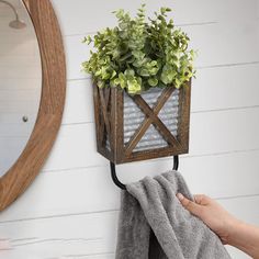 a person holding a towel in front of a potted plant hanging on a wall