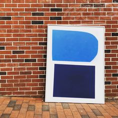 a blue and white painting sitting on top of a brick floor next to a wall