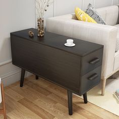 a living room with a couch, coffee table and white sofa in the background on a hard wood floor