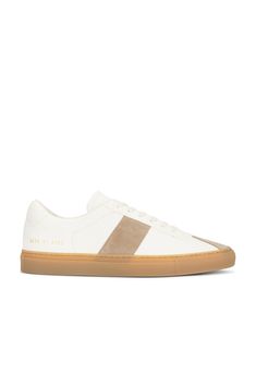 Find COMMON PROJECTS Tennis Trainer In White on Editorialist. Common Projects Tennis Trainer in White Leather upper and rubber sole. Made in Italy. Lace-up front. Suede paneling. Leather lining. COMF-MZ387. 2438-4102. About the designer: In 2004, armed with a desire to create the perfect sneaker, designers Flavio Girolami and Peter Poopat introduced a line of minimalist shoes to sneaker freaks around the world. Since the debut of their first collection, which featured only black, white, and gray sneakers, the line has grown to encompass more than your average laced-up low top. Today, Common Projects offers a range of colors, non-sneaker styles, and materials that are luxurious in look and feel. Custom Beige Leather Sneakers With Gum Sole, Beige Leather Custom Sneakers With Gum Sole, Modern White Custom Sneakers With Rubber Heel Cap, Custom Cream Leather Sneakers With Gum Sole, Cream Leather Custom Sneakers With Gum Sole, Cream Leather Sneakers With Contrasting Heel Counter, Cream Leather Sneakers With Contrasting Heel, Beige Leather Sneakers With Rubber Heel Cap, Suede Sneakers With Three Stripes Branding For Sports