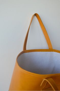 The perfect day-to-day tote that can fit all the essentials.This saffron colored Italian leather is saturated and structured. It's lined with a neutral French linen, and has an exterior pocket branded with the Dreamers logo.Measurements |16" L x 11" H x 6" W10" shoulder strap drop Dreamers Logo, Yellow Soft Leather Tote Shoulder Bag, Luxury Orange Tote Satchel, Saffiano Leather Shoulder Tote With Gold-tone Hardware, Orange Leather-handled Tote Satchel, Saffron Yellow, French Linen, Italian Leather, Leather Tote