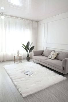 a living room with a couch, chair and rug on the floor in front of a window