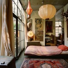 a bed sitting in a bedroom next to a window with lots of curtains on it