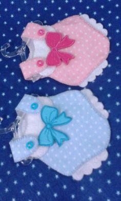 two baby bibs are laying on a blue blanket with white dots and pink bows