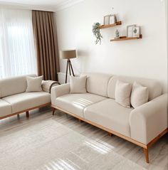 a living room with two couches and a lamp on the side table in front of a window