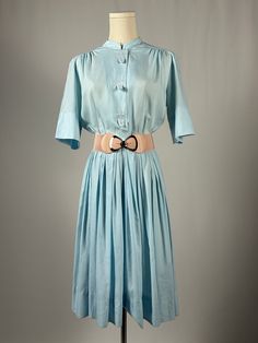 Baby blue Pacemaker Junior dress has so many lovely features. This dress features embroidered fleur di lis with loops that cover buttons.  Valoumonous stacked knife pleats and cross over skirt with snap closure.  (Belt pictured is not included) Good condition Has mild pilling and one very small spot on front.  Original belt is also missing. Measures Bust 19" Waist 14" Length shoulder to hem 40" Please keep in mind that when buying vintage items, you are purchasing something that has been pre-loved.  Most vintage items show some blemishes, imperfections, and wear, but that is also what makes them so unique.  We do our best to photograph/disclose the condition of the item as best we can.  Vintage items are at least 20 years old.  Prices reflect condition, age and quality.  Items are sold as Pleated Full Skirt Dresses For Daywear, Button-up Daywear Dress With Pleated Waist, Light Blue Collared Daywear Dress, Light Blue Collared Dress For Daywear, Light Blue Collared Day Dress, Blue Vintage Dress With Buttons For Spring, Spring Blue Vintage Dress With Buttons, Daywear Full Pleated Skirt Dress, Fitted Pleated Daywear Dress