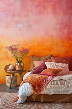 a bed sitting in front of a pink and orange wall with flowers on top of it