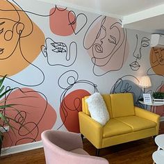 a living room filled with furniture next to a wall covered in colorful faces on it