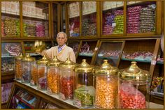 a man standing behind a counter filled with lots of candy