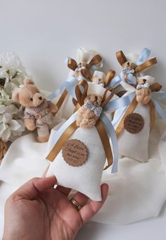 someone is holding two teddy bears in their wedding gowns and they are tied with ribbons