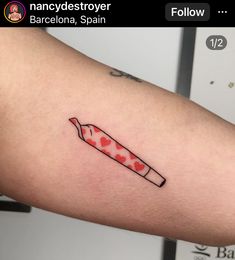 a red and white knife with hearts on it's side tattooing someones arm