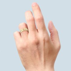 a person's hand with a gold ring on their left thumb and the middle finger up