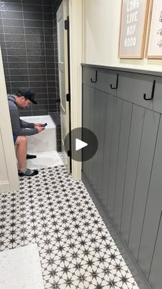 a man sitting on a toilet in a bathroom next to a tiled floor and wall