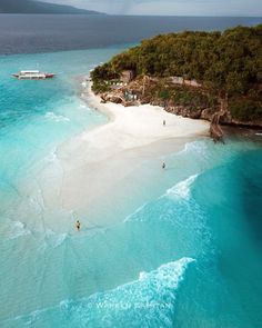 two people are standing on the beach in front of an island with white sand and blue water