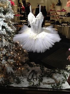 a ballerina tutule is displayed in front of a christmas tree and other holiday decorations