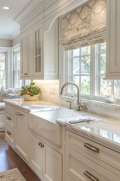 a kitchen with white cabinets and marble counter tops