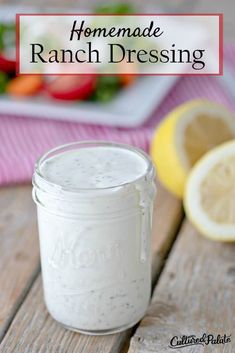 homemade ranch dressing in a mason jar on a wooden table with lemons and salad in the background