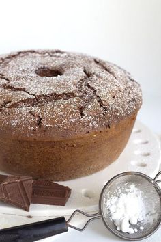 a chocolate cake with powdered sugar on top and two spoons next to it