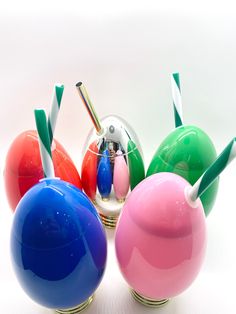 four colorful glass vases with toothbrushes sticking out of the top and bottom