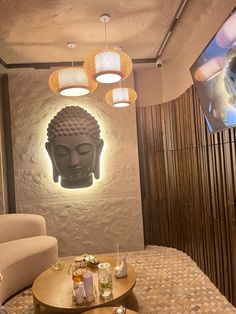 a living room filled with furniture and a buddha head on the wall