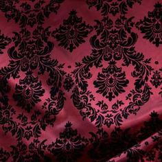 a red and black damask fabric with an intricate design on it's side