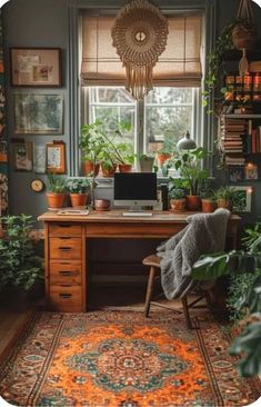 a desk with plants and pictures on the wall above it, in front of a window