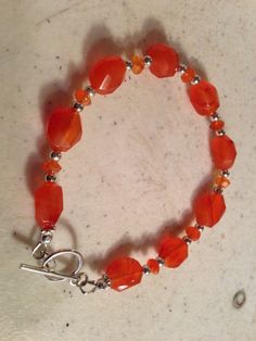 This orange bracelet created by Jewelry By Luet and Co is made of:  orange carnelian gemstones, sterling silver:   beads, toggle clasp and findings.  This bracelet measures 7 1/2 inches. WE OFFER FREE SHIPPING WITHIN THE UNITED STATES. All of our jewelry is unique and custom designed.  We would love to assist you with any custom orders or needs for special occasions! We appreciate you shopping with Jewelry By Luet and Co and hope you will do so often!  See more items from my shop: http://www.ets Orange Bracelet, Orange Carnelian, Gemstone Beads Jewelry, Beaded Jewellery, Bracelet Sterling Silver, Toggle Clasp, Silver Beads, Sterling Silver Bracelets, Custom Orders