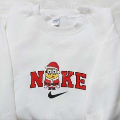 Nike Christmas x Minion Santa Claus Cartoon Embroidered Sweatshirt, Disney Characters Movie Merry Christmas Embroidered Shirt, Best Christmas Day Gift Ideas Step into the enchanting world of Tinicloset, where the holiday spirit comes to life in the most adorable and festive way possible. Our store is a treasure trove of custom embroidered apparel, featuring delightful... White Christmas Tops With Embroidered Graphics, White Top With Embroidered Logo For Christmas, Christmas White Embroidered Tops, White Tops With Embroidered Logo For Christmas, White Tops With Custom Embroidery For Christmas, Minion Dress Up, Minion Dress, Red Suit, Embroidered Clothes