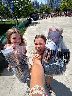 two girls are holding up their makeup products in the air and smiling at the camera