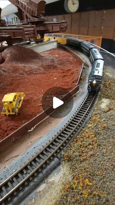 a toy train is on the tracks near a pile of dirt