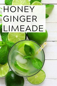 a glass filled with limeade next to sliced limes and mint on a white wooden table