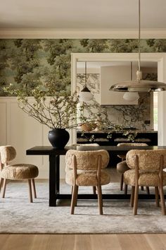 a dining room table with chairs and a vase filled with flowers on top of it