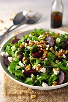 a salad with beets, feta cheese and walnuts in a white bowl