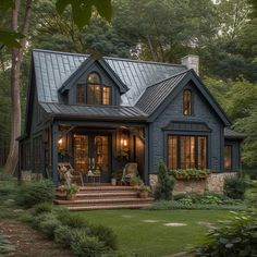 a black house with lots of windows and steps leading up to the front door is surrounded by greenery