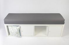 a white cabinet with a gray cushion on top