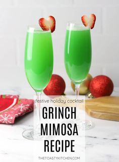 two glasses filled with green mimosa and topped with strawberries on the rim