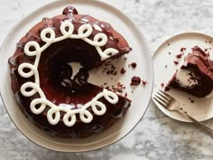 a piece of chocolate cake on a plate next to a slice of cake with white icing